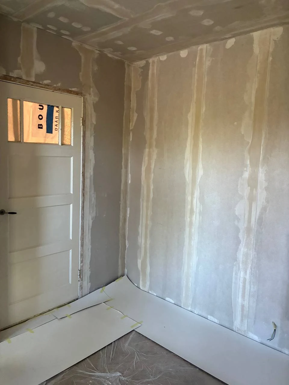 Gipswanden en plafond met afgewerkte naden en schroefgaten in een kamer