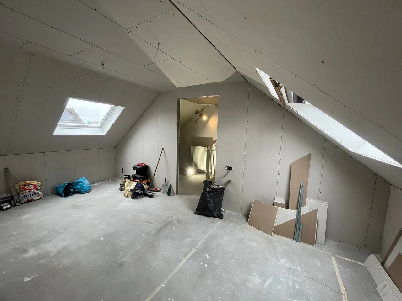 Gemonteerde gipsplaten op de wanden en het schuine plafond van een zolder